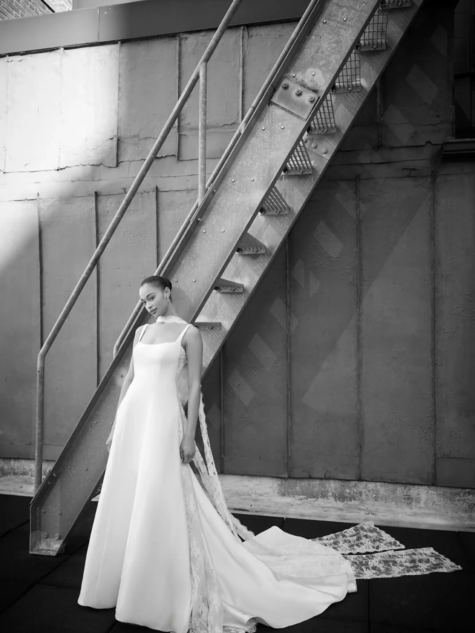Vestido de satén minimalista con velo largo sobre una escalera
